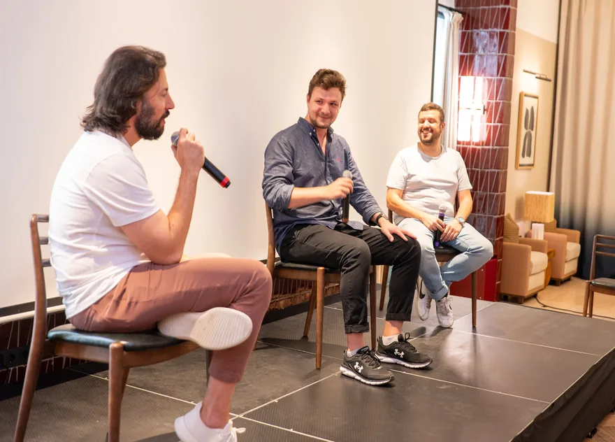A speaker with a microphone alongside two others on stools